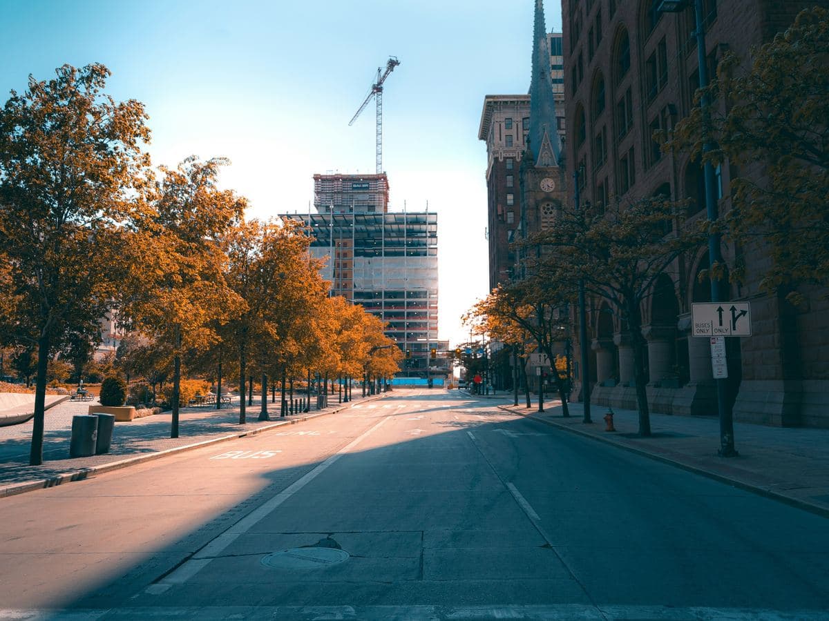 A tree-lined downtown Cleveland street in autumn, with historic stone buildings and a clock tower