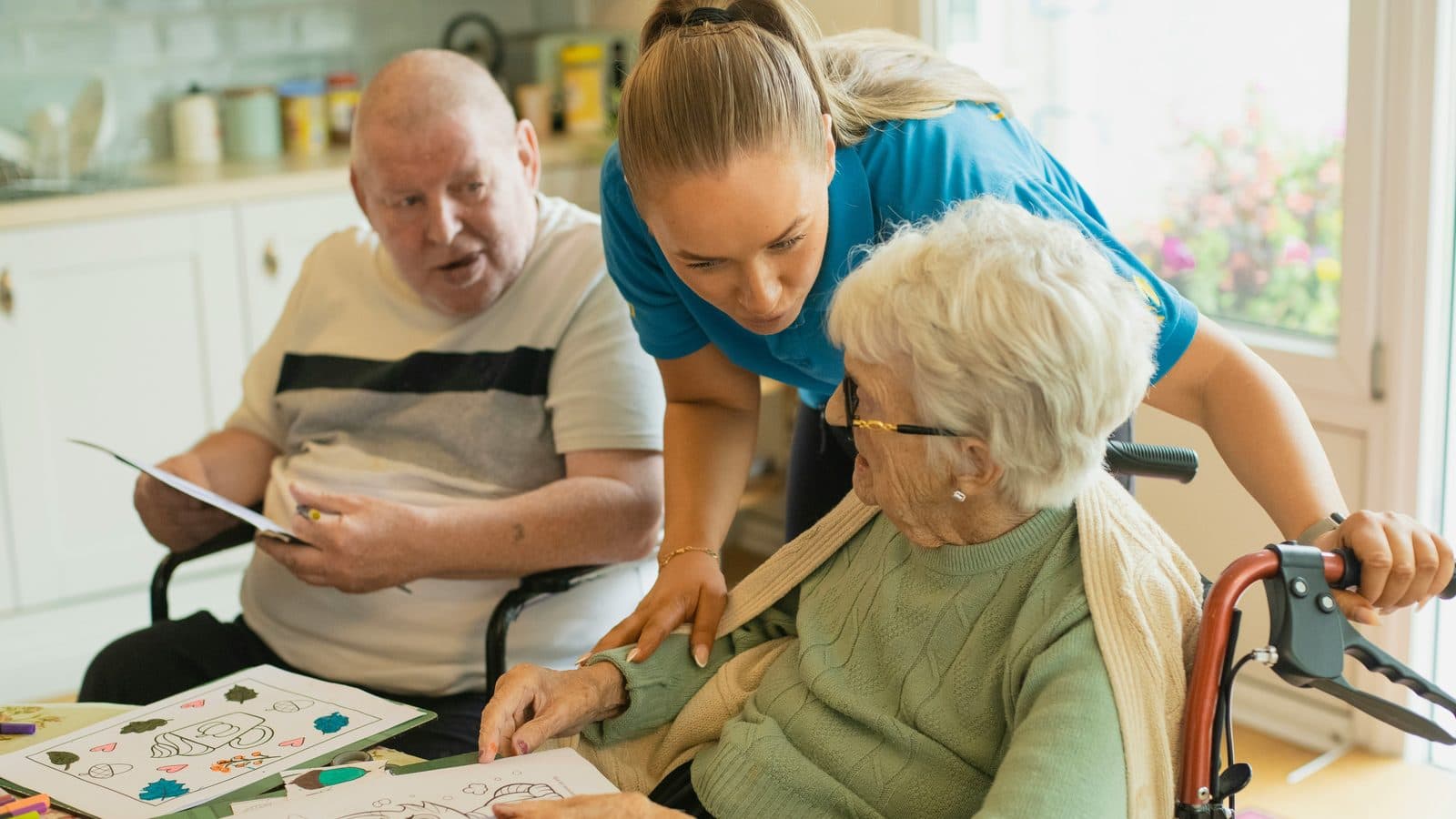 A Serenity Life Home Care caregiver helping a senior couple with an activity at their kitchen table
